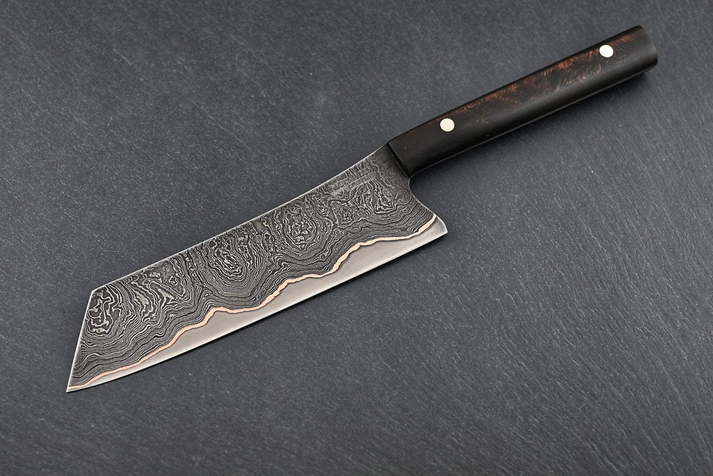 Santoku-Messer mit Damastklinge und schwarzem Heft, seitliche Ansicht mit Klingenrücken.